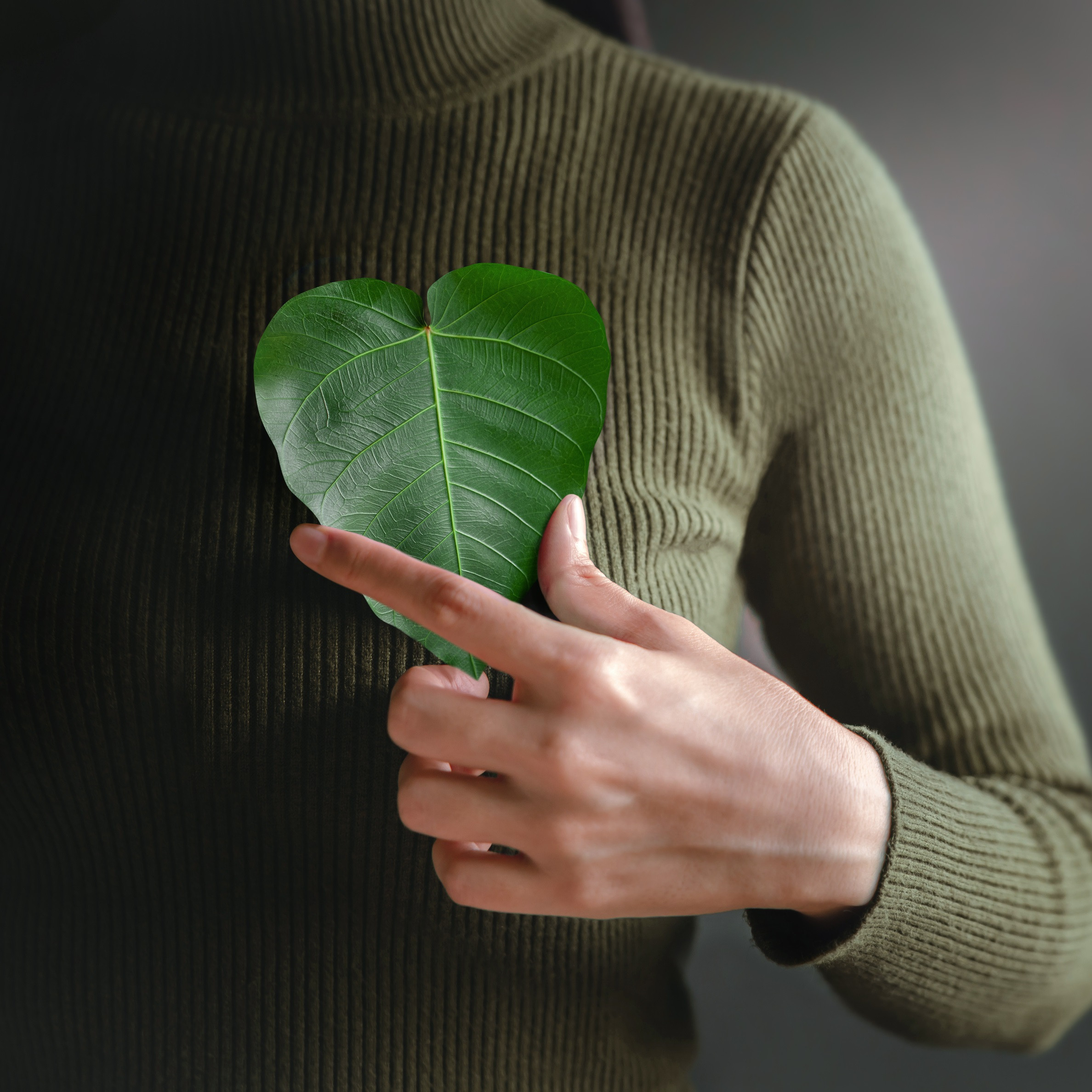 Frau hält Blatt vor ihr Herz