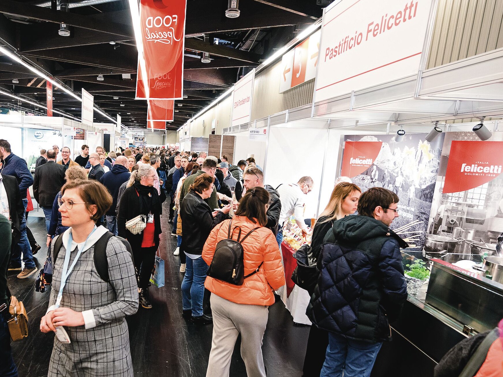 Eine Gruppe von Menschen in einem Raum, darunter Männer und Frauen, die stehen und miteinander interagieren.