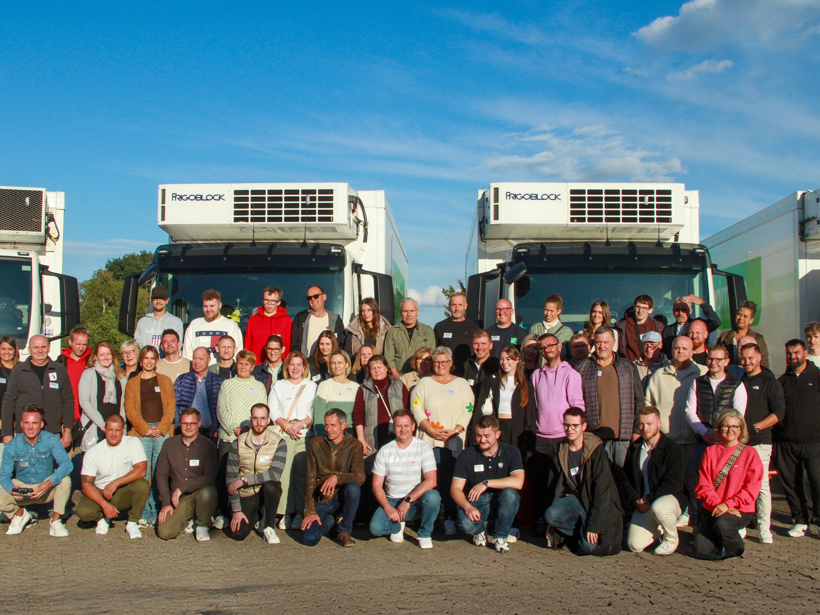 Eine Gruppe von Menschen posiert vor Lastwagen.
