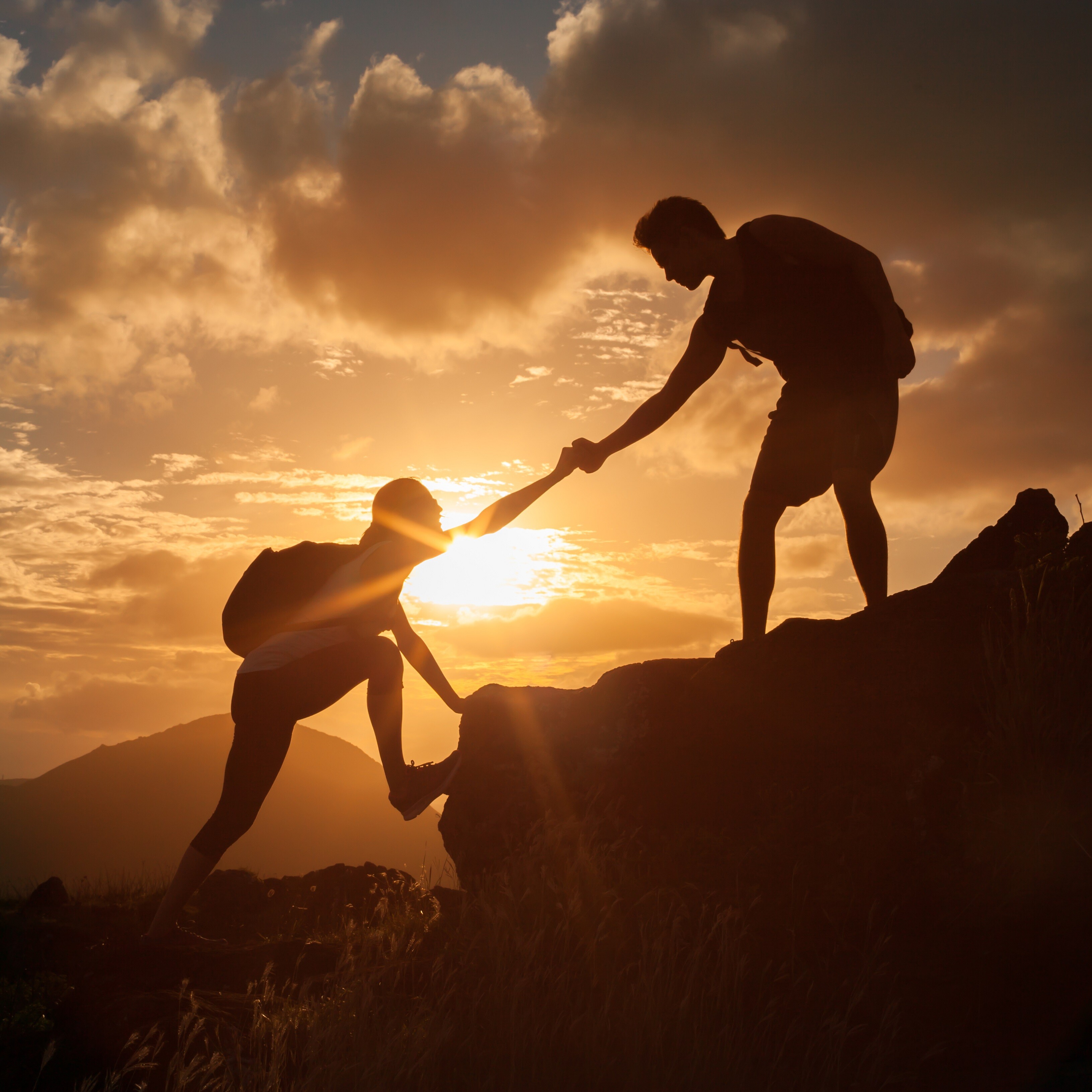 Eine Gruppe von Menschen beim Bergsteigen im Gegenlicht.