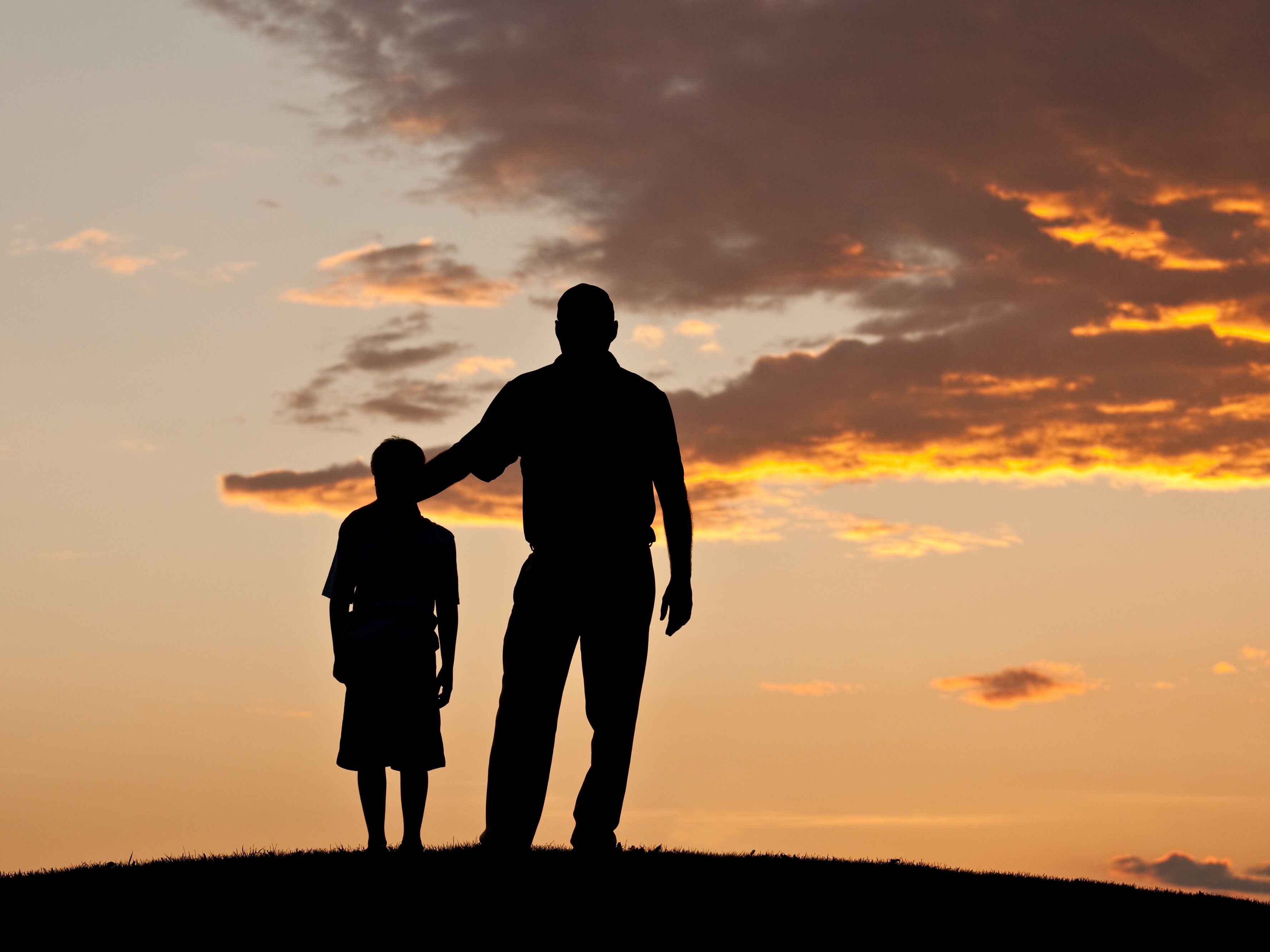 Respekt Ein Mann und ein Kind stehen auf einem Hügel im Freien.