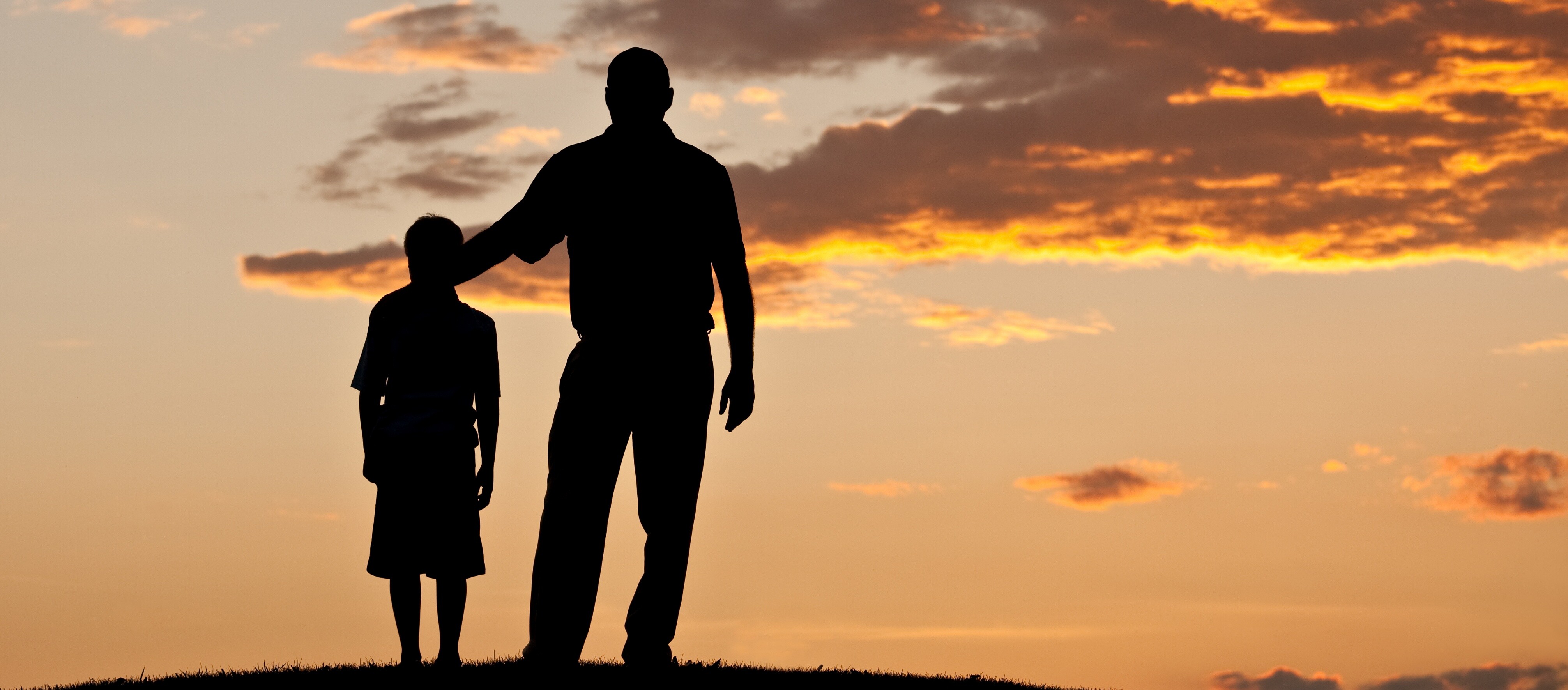 Ein Mann und ein Kind stehen auf einem Hügel im Freien.