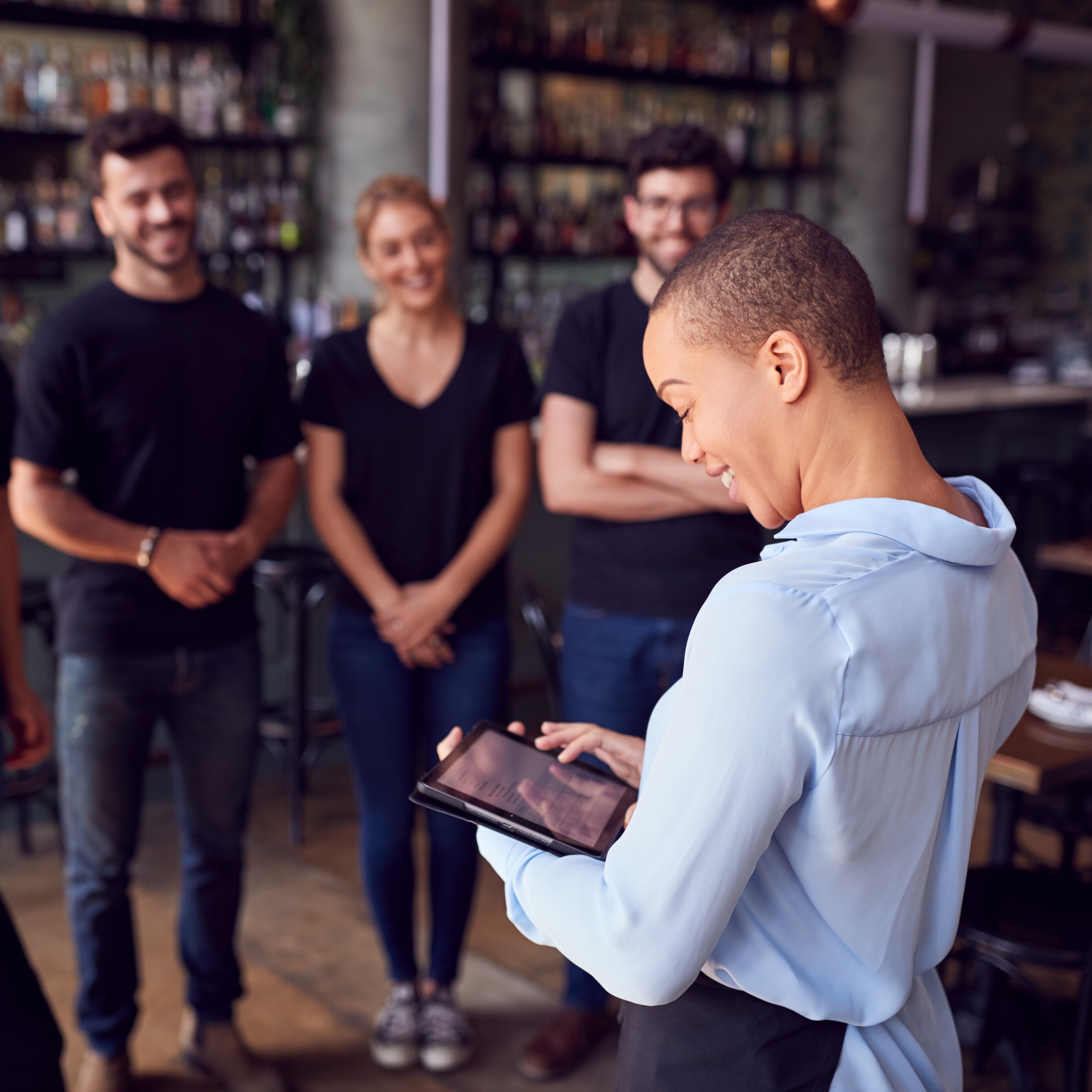 Eine Frau hält ein Tablet vor einer Gruppe von Menschen.