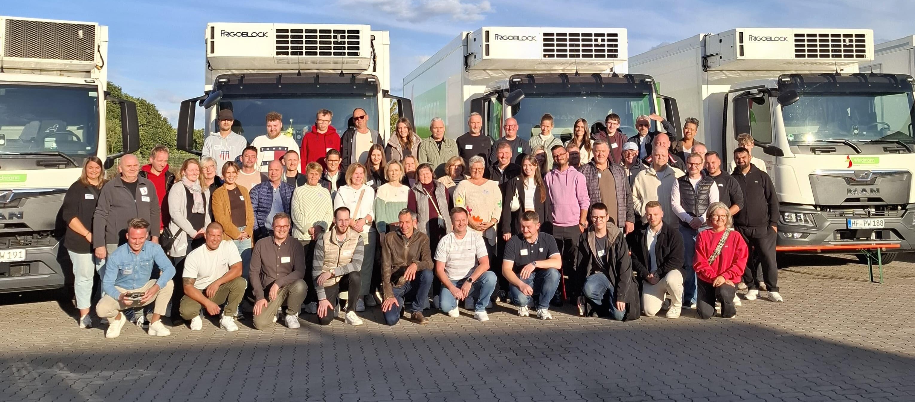 Eine Gruppe von Menschen posiert vor Lastwagen.