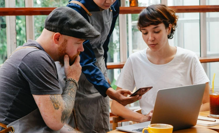 Eine Gruppe von Menschen betrachtet einen Laptop.
