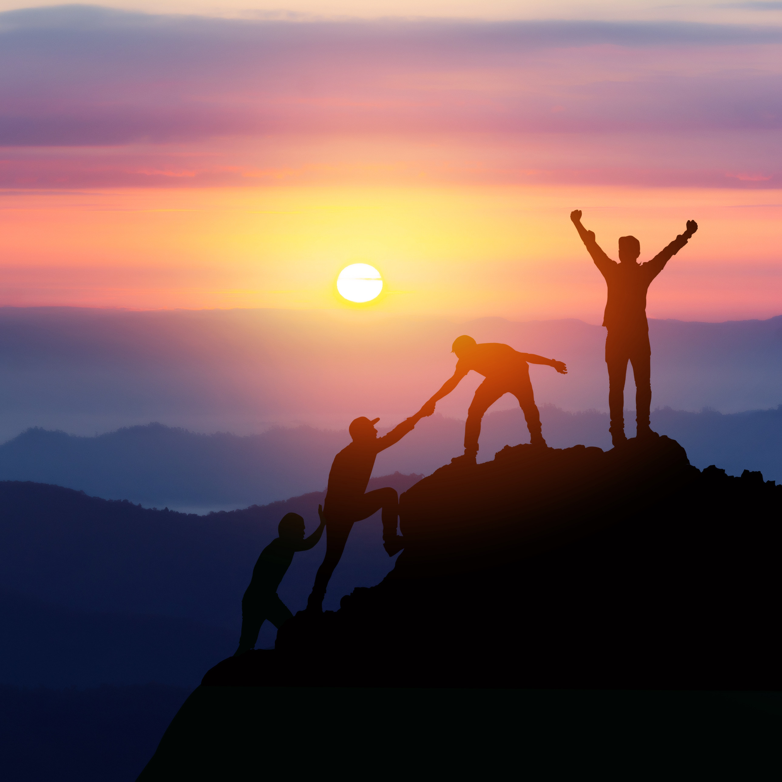 Eine Gruppe von Menschen beim Bergsteigen im Gegenlicht.